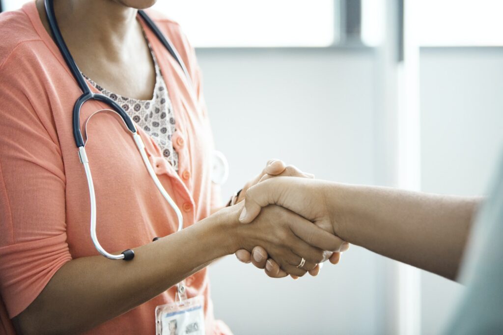 Midsection Of Female Doctor Shaking Hands With Patient