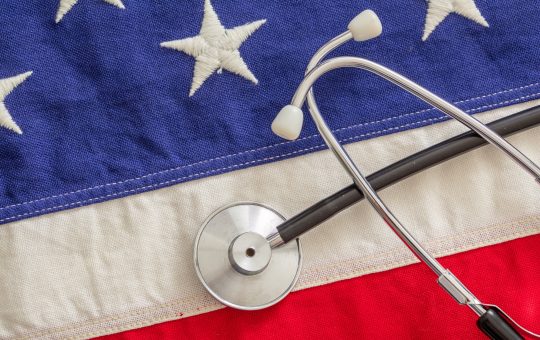 US health. Medical stethoscope on a USA flag, top view.